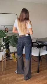 Pantalón de jean de tiro medio con diseño bicolor, combinando un tono azul oscuro en la parte superior y un tono más claro en la parte inferior. Presenta una cintura con detalle de textura tipo animal print y costuras reforzadas en las rodillas.