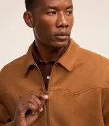 Campera masculina de estilo casual con cuello inglés, cierre frontal por cremallera, bolsillos laterales y ajuste elástico en el bajo. Presenta detalles de recortes en la parte superior delantera.