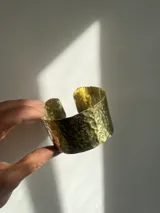 Brazalete ancho de bronce color dorado con textura martillada.