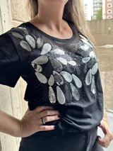 Remera negra de mangas cortas, con tul bordado con lentejuelas plateadas en la parte superior.