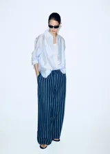 Camisa oversize de manga larga a rayas celestes y blancas, con cuello solapa camisero y cierre frontal de botones.