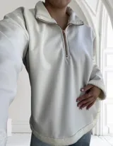 Buzo color crudo de ecocuero con cuello alto, cierre metálico dorado y puños con elástico.