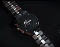 Reloj cronógrafo de la colección Imperial, con caja de madera de ébano oscuro y bisel técnico. La esfera negra presenta subdiales con textura de madera natural, indicador de fase lunar y fechador. La malla combina eslabones de acero inoxidable pulido con madera de ébano, ofreciendo un diseño sofisticado y resistente.