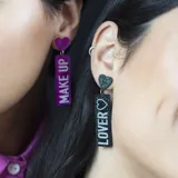 Aros colgantes con forma rectangular con glitter y la leyenda "Make Up" en uno y "Lover" en el otro.