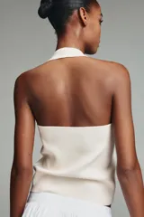 Top de punto negro con cuello halter y escote redondo, decorado con tachas metálicas plateadas distribuidas por toda la prenda.