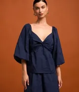 Blusa azul marino de tricolina con bordado de cocoteros, escote corazón, mangas largas abullonadas y busto retorcido.