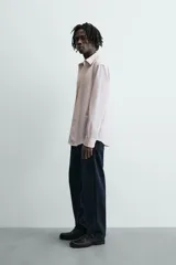 Camisa slim fit de algodón, color beige con rayas verticales blancas. Presenta cuello italiano, manga larga con puño de botón y cierre frontal de botonadura.
