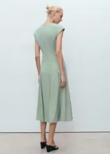 Vestido midi color verde menta, con manga corta, escote en V y diseño evasé con detalle de costuras visibles. Incorpora cierre de cremallera en la parte posterior.