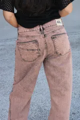 Jean de corte recto y tiro medio, color rosado con efecto acid wash y costuras diagonales en negro.