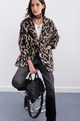 Tapado cruzado de corte oversize confeccionado en paño con estampado de leopardo. Presenta solapas clásicas, cierre frontal con botones y bolsillos aplicados.