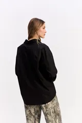 Camisa de algodón color blanco, de corte relajado y estilo western. Presenta detalle de tachas metálicas en la parte superior delantera y mangas largas con puños.