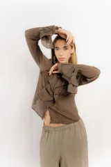 Camisa de estilo romántico confeccionada en algodón, con cuello alto, volados frontales y mangas largas con puños acampanados también decorados con volados.