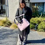 Bolso tipo tote y shopper de color negro, confeccionado en poliéster con amplio espacio interior, doble asa de mano y correa larga ajustable para llevar al hombro o cruzado.