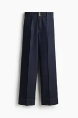 Jean de denim de algodón con leve stretch, corte wide leg de tiro alto, con pliegues frontales y dobladillo ancho.