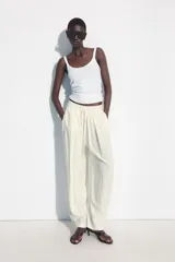 Pantalón fluido de tiro medio, color blanco, con cintura elástica ajustable con cordones, bolsillos laterales y bajo ajustable con trabilla y botón a presión.