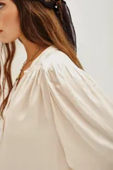 Camisa color crema de manga larga con cuello mao, botones a tono y frunces en mangas, espalda y hombros.