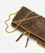 Cartera bandolera de tamaño mediano con estampado de piel de serpiente en tonos marrones y negros. Cuenta con asa de cadena dorada, solapa frontal y detalles de cierres metálicos con tiradores de cuero.