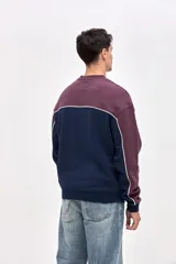 Buzo de cuello redondo en felpa con friza, de calce relajado. Presenta un diseño de bloques de color en azul marino y bordó, con detalles de vivos en color blanco que recorren el cuerpo y las mangas. Incluye un pequeño estampado con el logo de la marca en el pecho.