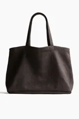 Bolso de playa color marrón, tipo tote, confeccionado en tejido texturizado con dos asas superiores.