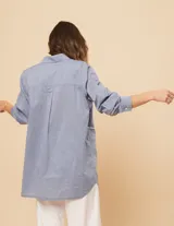 Camisa celeste de algodón con corte oversized, botones frontales a tono y vivos blancos ondulados en el frente.