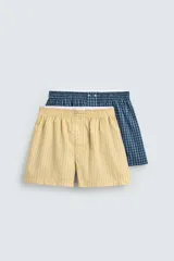 Pack de dos calzoncillos tipo bóxer de popelín de algodón. Uno es amarillo con rayas verticales azules y el otro es azul oscuro con estampado a cuadros. Ambos tienen cintura elástica con efecto doble combinado a contraste y bragueta delantera con botones.