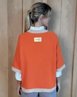 Buzo de lana lambswool en color lila, con cuello redondo, puños y ruedo en tono beige contrastante. Presenta un diseño holgado de manga corta con terminación acanalada.