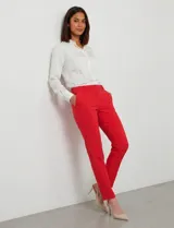 Pantalón sastrero de corte slim, color blanco, con pretina anatómica y panel interno modelador. Presenta bolsillos laterales tipo ojal, bolsillos traseros simulados y nervadura vertical marcada en el frente.
