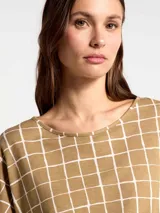 Blusa de manga corta con cuello redondo y estampado de cuadrícula blanca sobre fondo color tostado.
