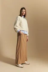 Sweater color crema con mangas abullonadas y puños elastizados. Presenta una textura tejida en relieve con patrón de ladrillos en el cuerpo y rayas horizontales en las mangas.