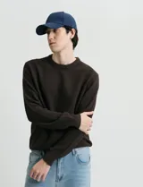 Sweater de punto con escote redondo, confeccionado en algodón con textura de punto fantasía en cuerpo y mangas, y terminaciones en punto canalé en cuello y puños.