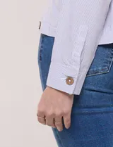 Camperita de lino liviana, marca Dash, con estampado botánico de hojas en tonos azules, verdes y tostados sobre base blanca. Presenta cierre frontal con botones, cuello clásico y bolsillos aplicados en el pecho.