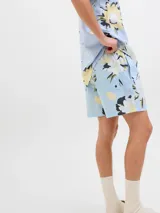 Short de baño de tiro medio con estampado floral en tonos claros sobre fondo celeste. Cuenta con cintura elástica con cordón ajustable, bolsillos laterales y un bolsillo trasero.