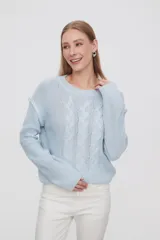 Sweater de punto color celeste, con diseño de trenzas frontales, cuello redondo y corte holgado.
