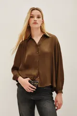 Camisa de viscosa en color marrón, con cuello clásico, cierre frontal de botones y mangas largas con puños abotonados.