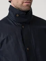 Chaqueta de hombre color azul marino, confeccionada en tela encerada impermeable y cortaviento. Cuenta con cuello de cotelé, cierre frontal con broches y cremallera, y múltiples bolsillos exteriores e interiores. El interior está forrado en franela y tiene relleno de THERMORE, hecho de fibras recicladas.