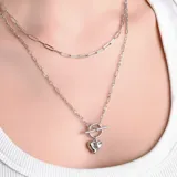 Collar doble de cadena plateada con eslabones rectangulares y dije de corazón con cierre tipo barra en T.