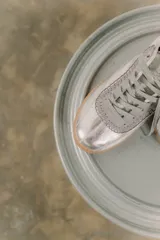 Zapatillas bajas de cuero color crema con detalles en marrón y cordones blancos.