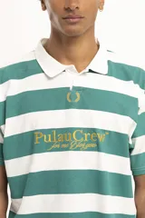 Remera de manga corta color verde oscuro, estilo polo con cuello y abertura frontal. Presenta un bordado central con el texto "PulauCrew" y un laurel en la parte superior.