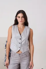 Chaleco de escote en V con cierre frontal mediante botones, bolsillos delanteros y estructura entallada en color plateado.