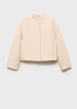 Chaqueta de algodón color crema, con cuello redondo, cierre frontal oculto y mangas largas con detalles de desflecado en los laterales.