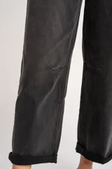 Jean de corte baggy con tiro medio, confeccionado en denim de color gris lavado. Presenta un diseño de pierna ancha con costuras horizontales a la altura de la rodilla y cierre frontal con botón y cremallera.