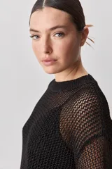 Sweater calado de punto negro, con cuello redondo y mangas largas, de diseño liviano ideal para superposiciones.