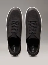 Zapatillas de perfil bajo Calvin Klein, confeccionadas en tejido de punto transpirable color negro. Presentan puntera revestida, trabilla trasera de piel y suela de goma blanca con logo grabado en la mediasuela.
