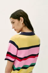 Top de punto de manga corta con cuello polo y cierre frontal de botones, con diseño de franjas horizontales multicolor en tonos amarillo, rosado, azul marino, rojo y verde.