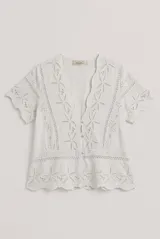Camisa azul de manga corta confeccionada en tejido broderie con diseño calado y floral. Cuenta con escote en V y cierre frontal de botones.
