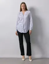 Blusa de lino estampada a rayas verticales en tonos blanco, verde, violeta, amarillo y rosa. Cuello a la base con escote en V y abertura central con botones. Delantera con bolsillos de parche. Mangas largas regulables con presilla y botón.