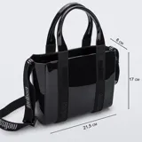 Cartera tipo tote bag Melissa modelo Mini Dulce, color negro brillante, fabricada en Melflex (PVC flexible y vegano). Cuenta con doble asa de mano y una correa ajustable y removible con el nombre de la marca estampado.