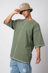Remera verde militar de corte oversize, con mangas 3/4 y costuras a la vista en color blanco.