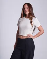 Remera de morley de algodón, color crudo, con cuello redondo, manga corta y terminaciones con borde fruncido.