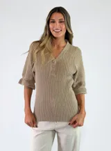 Top de tejido de punto color beige, con escote en V y botones frontales. Presenta mangas cortas con textura combinada y diseño acanalado en el cuerpo.